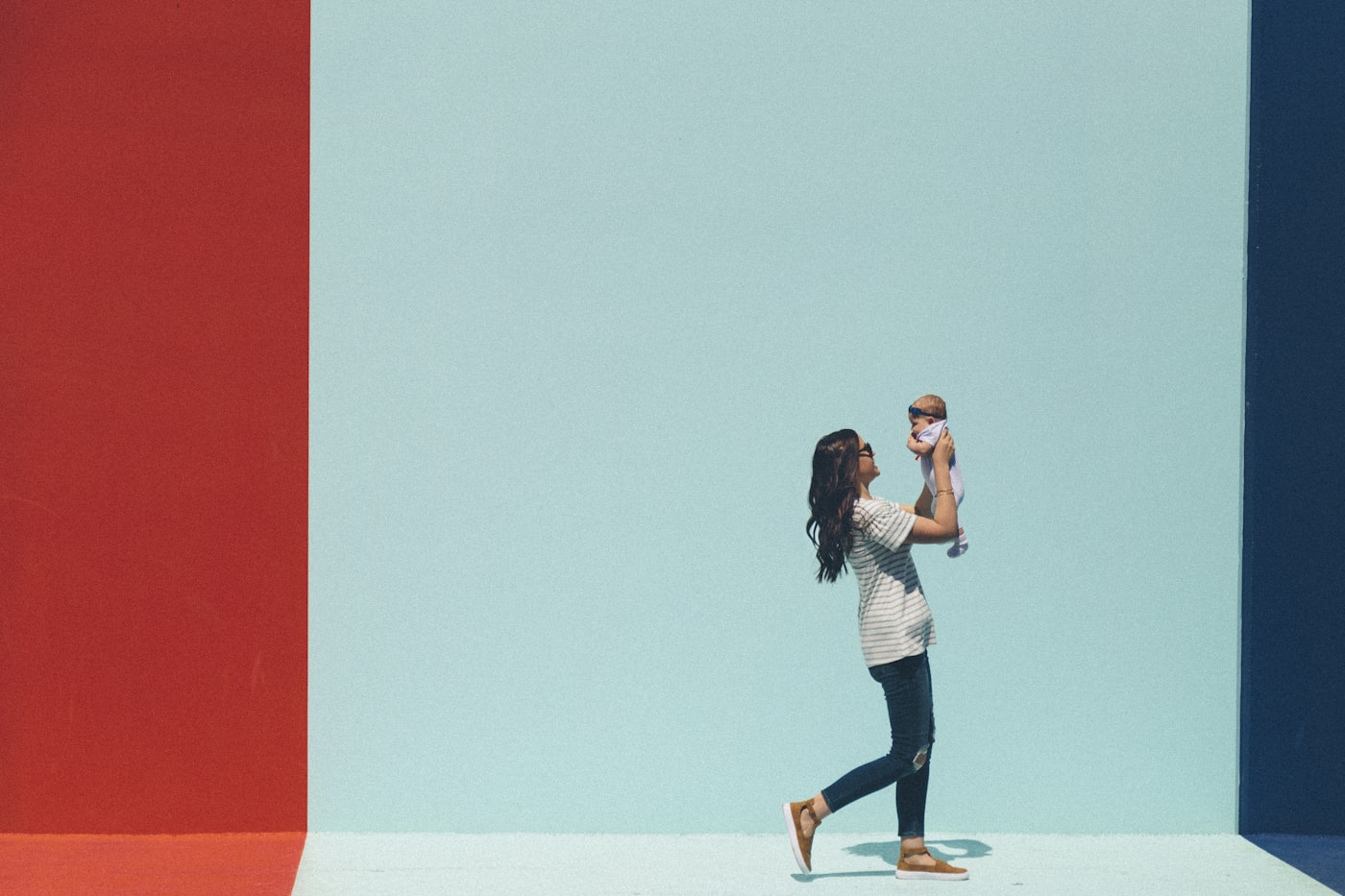 A woman holding a baby against a turquoise wall