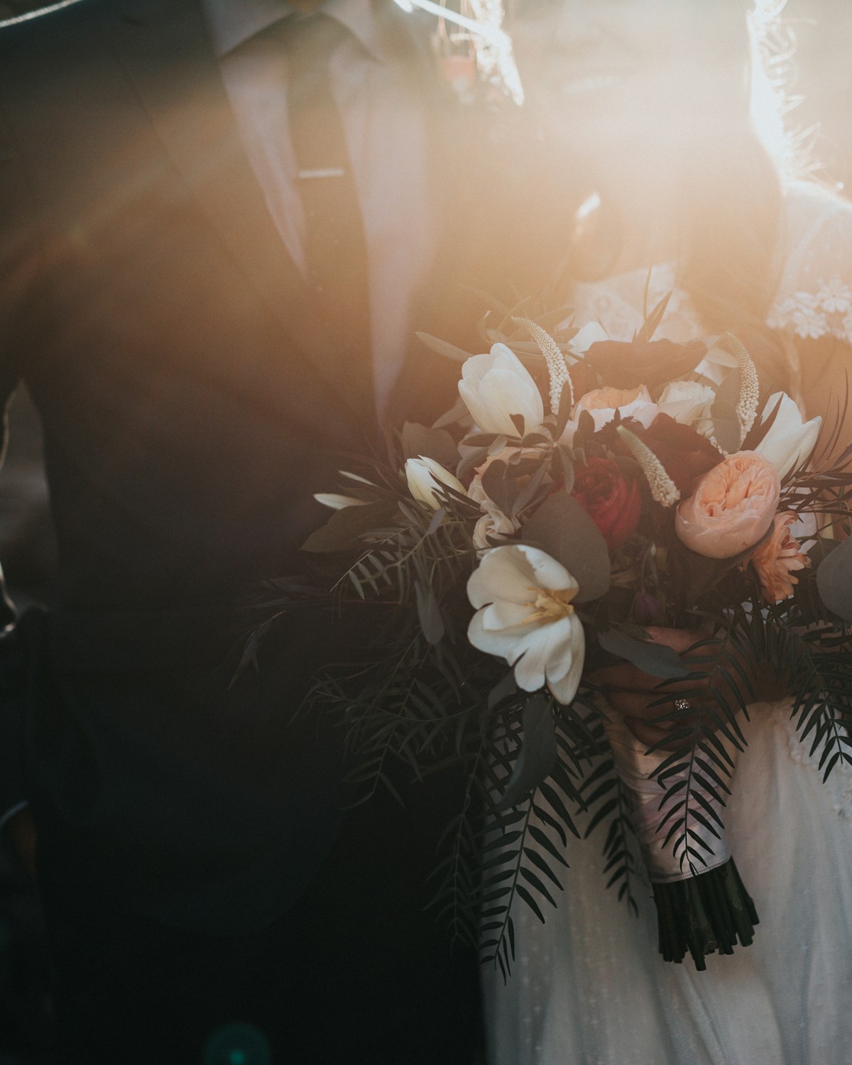 A couple holding a bouquet in warm evening light