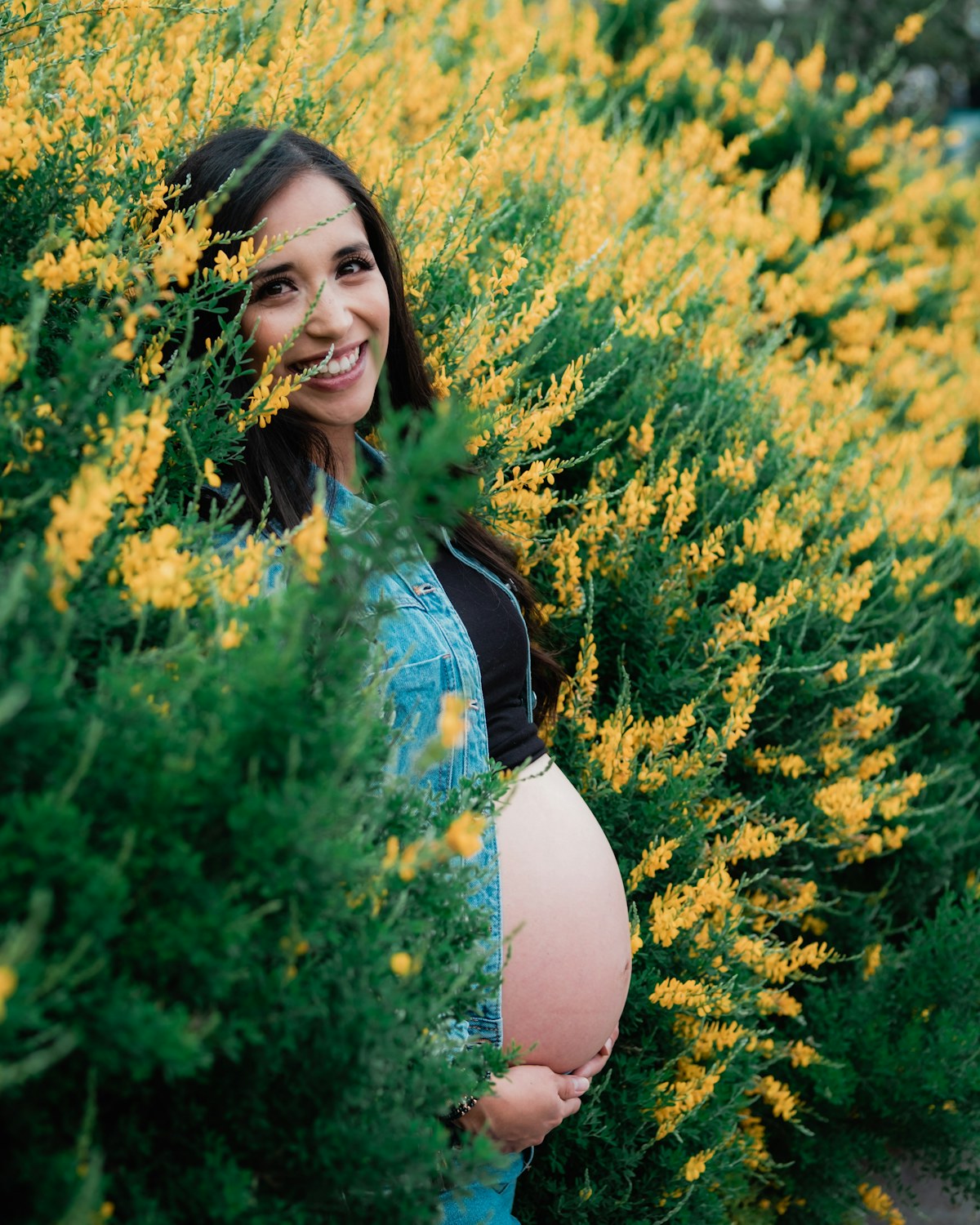 An expectant mother standing among yellow flowers